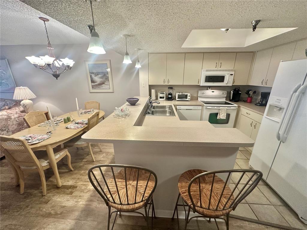 A kitchen with light-colored cabinets and a breakfast bar overlooks a dining area — 6035 SEA RANCH DRIVE UNIT 410, HUDSON, FL