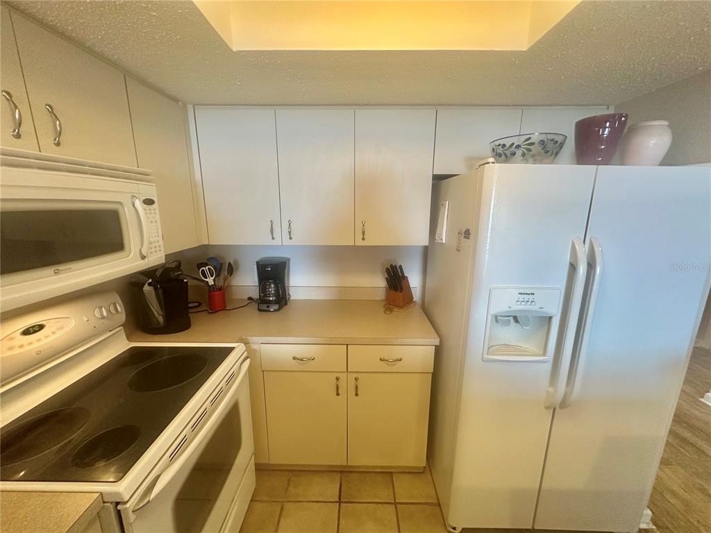 A kitchen features white cabinets, white appliances, and light-colored countertops — 6035 SEA RANCH DRIVE UNIT 410, HUDSON, FL