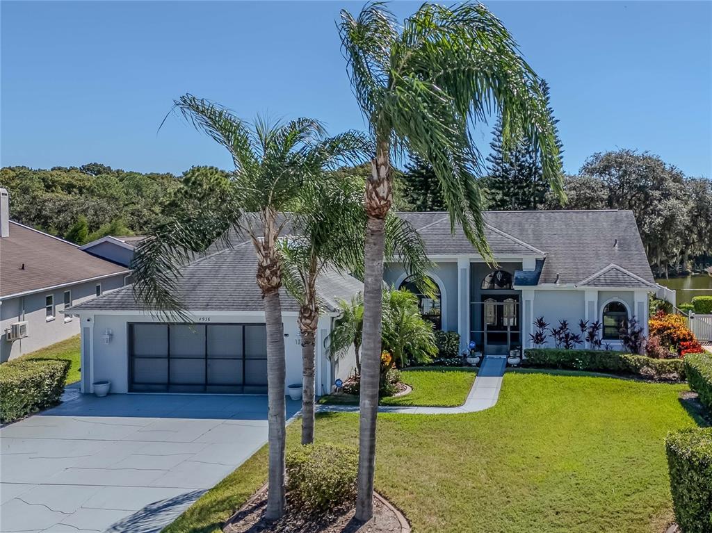 A single-story house with a gray garage, palm trees, and a front walkway — 4938 YELLOWSTONE DRIVE, NEW PORT RICHEY, FL