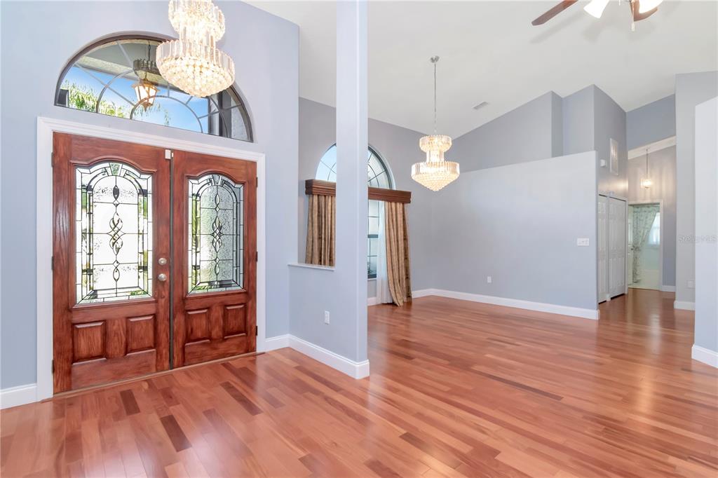 An entryway with hardwood floors, a double wooden door, and two crystal chandeliers — 4938 YELLOWSTONE DRIVE, NEW PORT RICHEY, FL
