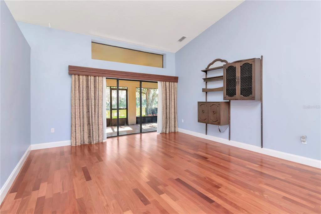 A living room features light blue walls, hardwood floors, and sliding glass doors to a patio — 4938 YELLOWSTONE DRIVE, NEW PORT RICHEY, FL