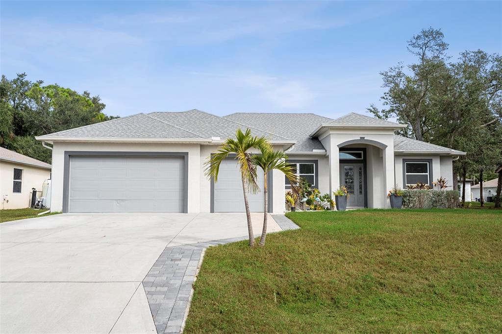 A single-story house with a gray roof, two garage doors, and a paved walkway — 3038 VELVET LANE, NORTH PORT, FL