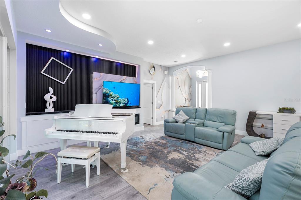 A living room features a white grand piano, blue leather sofas, and a black accent wall — 3038 VELVET LANE, NORTH PORT, FL