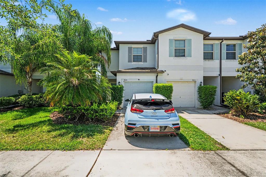 A light blue hatchback is parked in the driveway of a two-story suburban townhouse — 7655 GINGER LILY COURT, TAMPA, FL