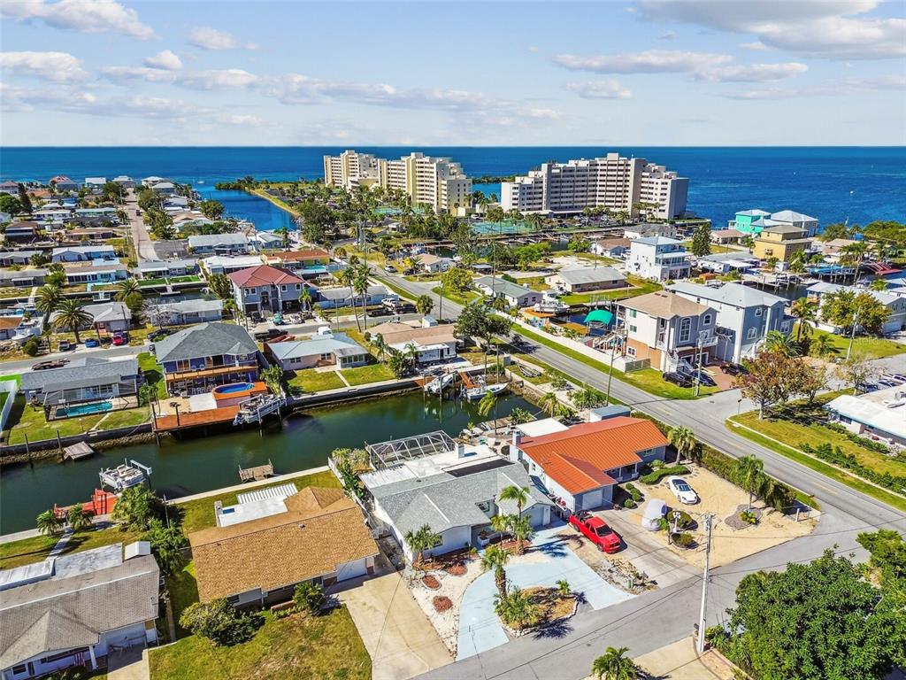 A screened-in pool patio overlooks a canal with boats docked in the background — 13711 ALLYN DRIVE, HUDSON, FL