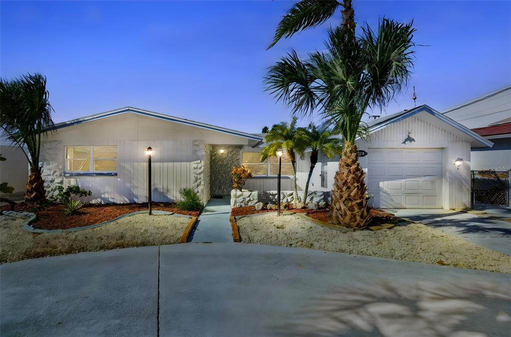 A single-story white house with a garage, palm trees, and a concrete driveway at dusk — 13711 ALLYN DRIVE, HUDSON, FL
