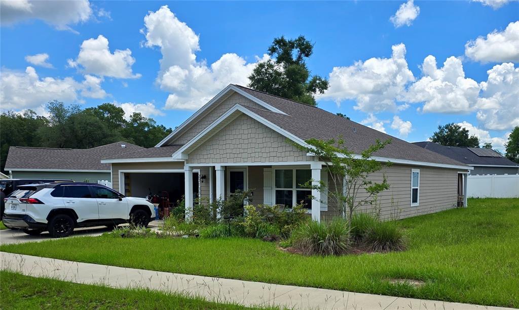 A single-story house with tan siding, a shingled roof, and a white SUV in the driveway — 20133 NW 249TH STREET, HIGH SPRINGS, FL