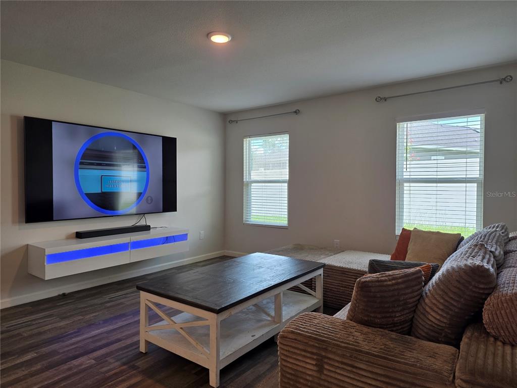 A living room features a wall-mounted television, a floating media console, and a sectional sofa — 20133 NW 249TH STREET, HIGH SPRINGS, FL