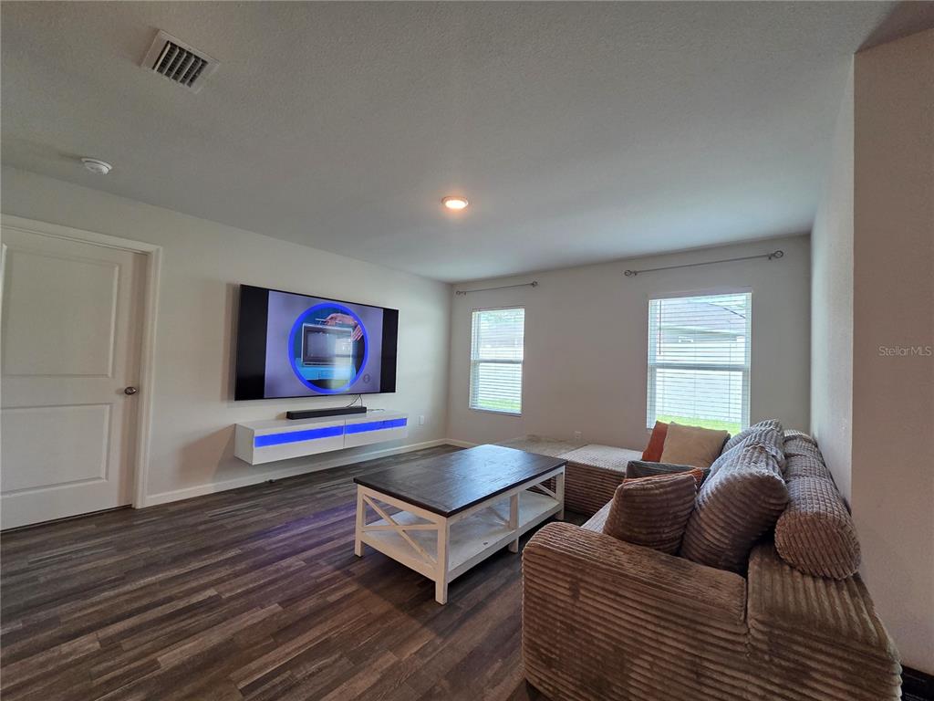 A living room features wood-look flooring, a wall-mounted television, a floating console, and a sofa — 20133 NW 249TH STREET, HIGH SPRINGS, FL