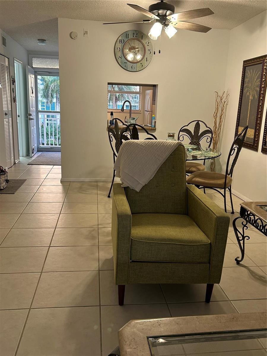 A green armchair sits in a dining area with tile floors and a wall clock — 1541 S Ocean Boulevard # 324, Pompano Beach FL 33062, POMPANO BEACH, FL