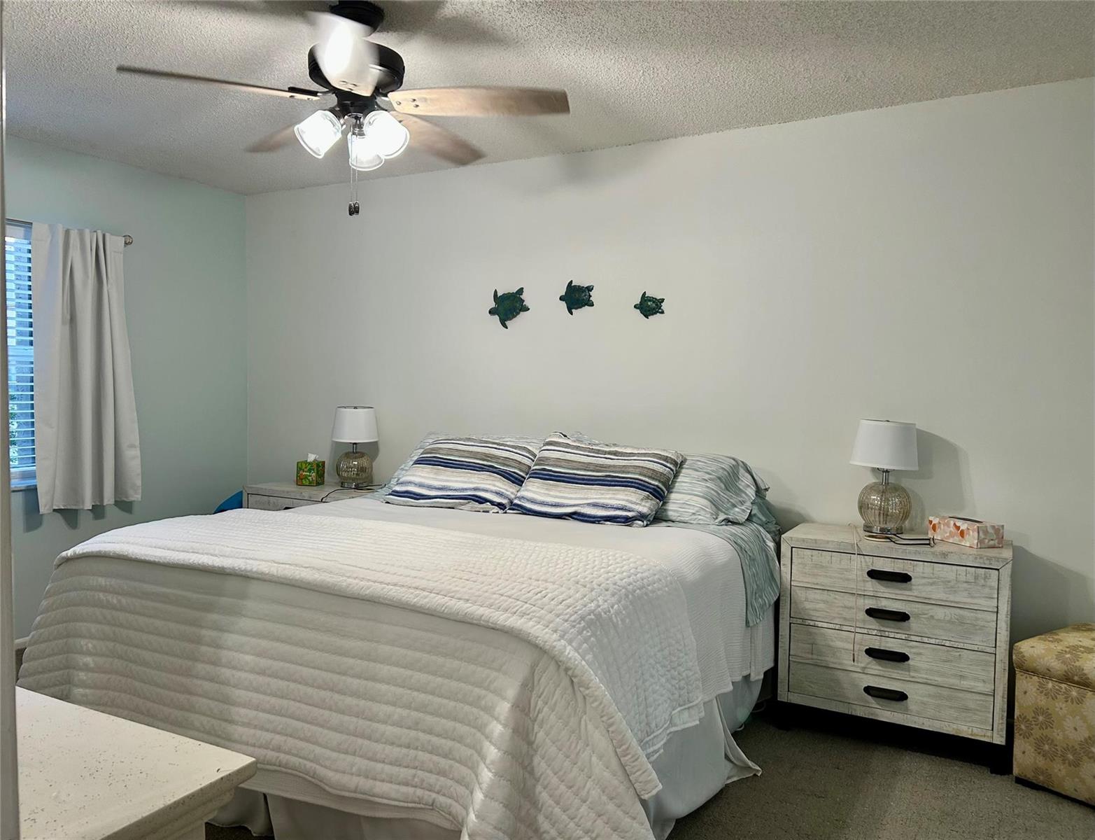 A bedroom features a bed with white bedding, two nightstands, and wall-mounted turtle decor — 1541 S Ocean Boulevard # 324, Pompano Beach FL 33062, POMPANO BEACH, FL