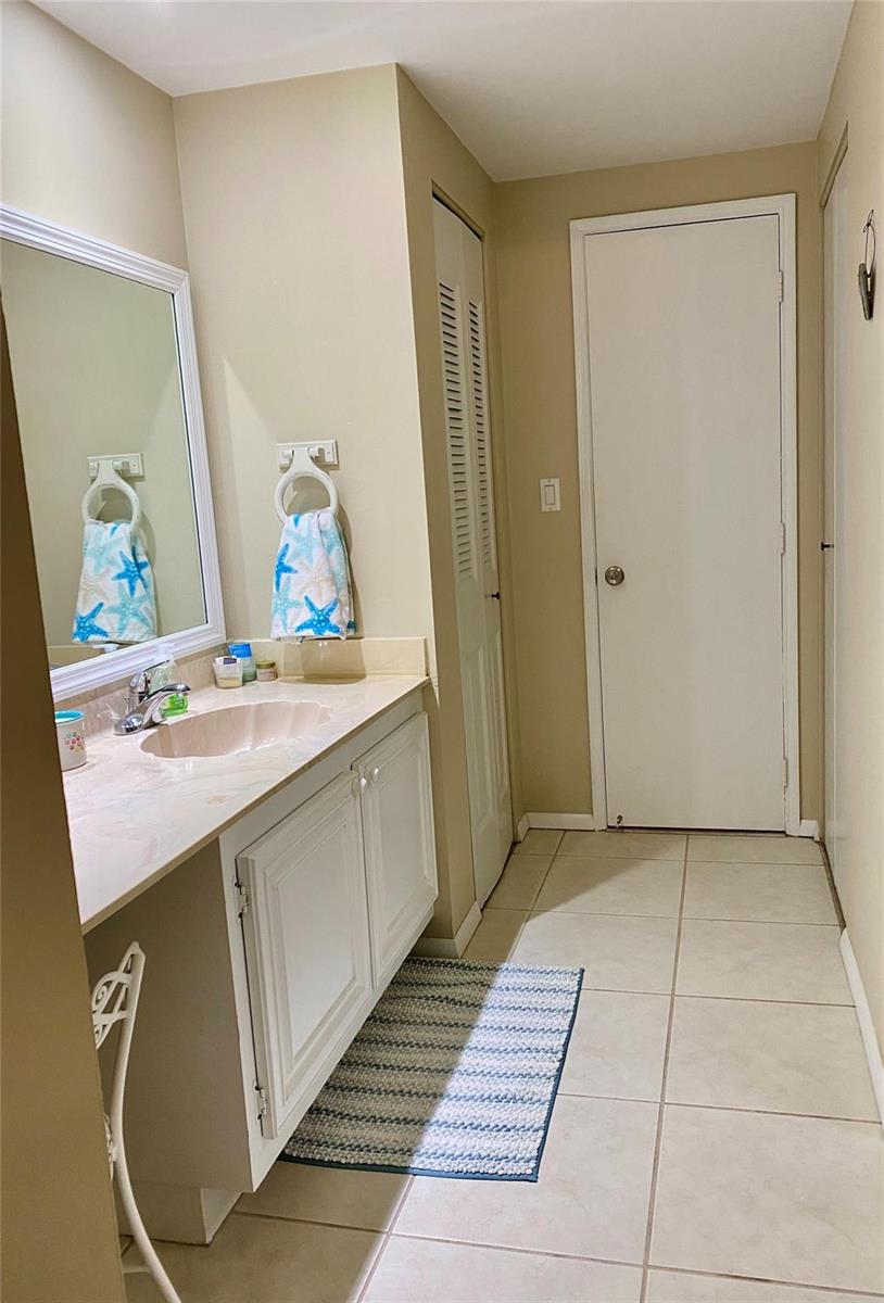 A bathroom features a vanity with a beige countertop, a white mirror, and tiled flooring — 1541 S Ocean Boulevard # 324, Pompano Beach FL 33062, POMPANO BEACH, FL