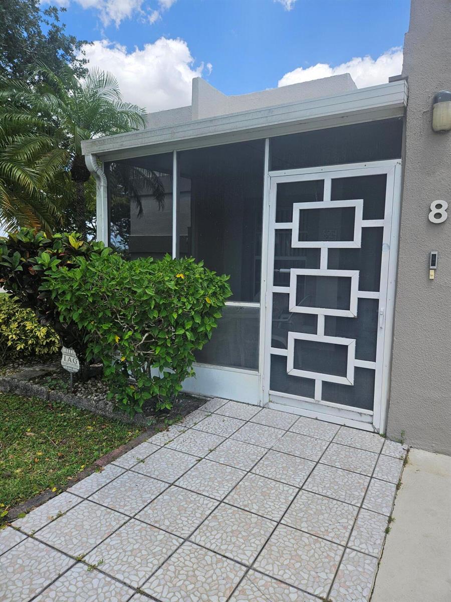 A tiled walkway leads to a screened-in front porch with a decorative white metal door — 18999 Stewart Circle # 8, Boca Raton FL 33496, BOCA RATON, FL