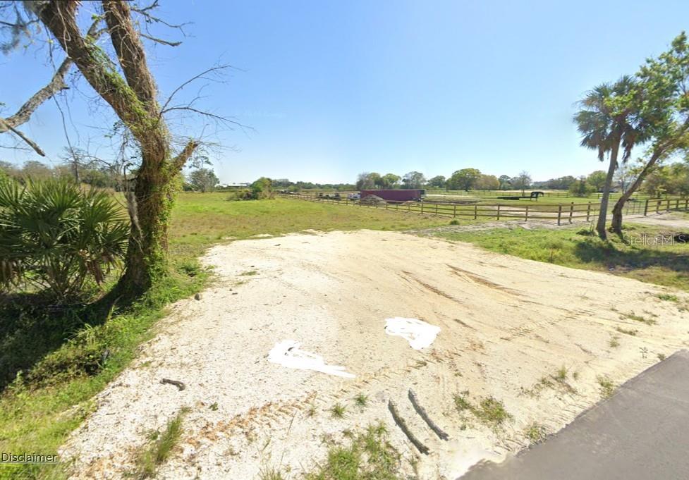 A dirt driveway leads into a large, open grassy field enclosed by a wooden fence — 1376 NE 48TH AVENUE, OKEECHOBEE, FL