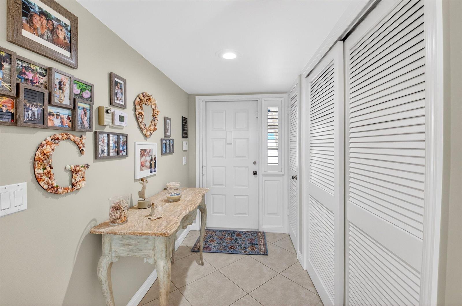 An entryway features a console table, a gallery wall, and white louvered closet doors — 75 Venetian Drive # 2, Delray Beach FL 33483, DELRAY BEACH, FL