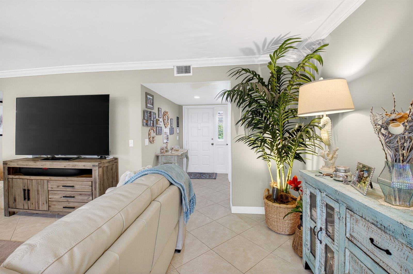A living room features a television on a wooden console, a sofa, and a plant — 75 Venetian Drive # 2, Delray Beach FL 33483, DELRAY BEACH, FL