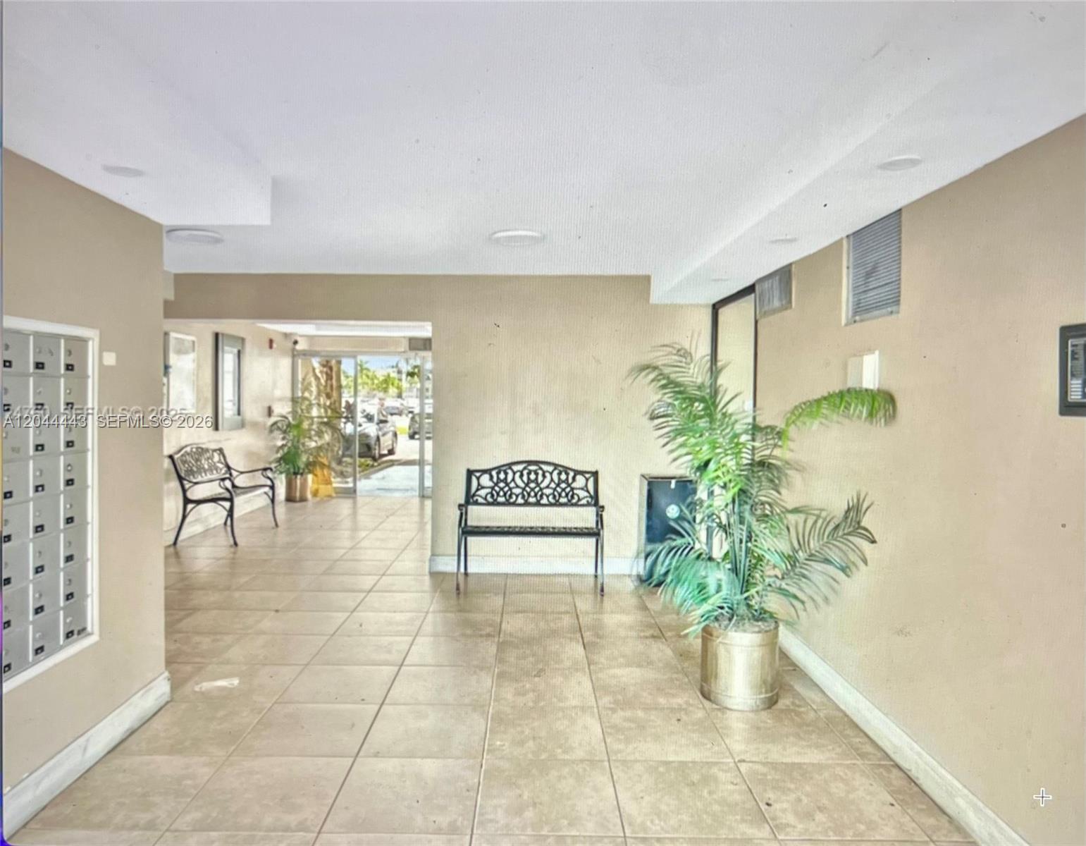 An indoor lobby area features tiled floors, a metal bench, and a potted palm plant — 1780 NE 191st St # 2, Miami FL 33179, MIAMI, FL