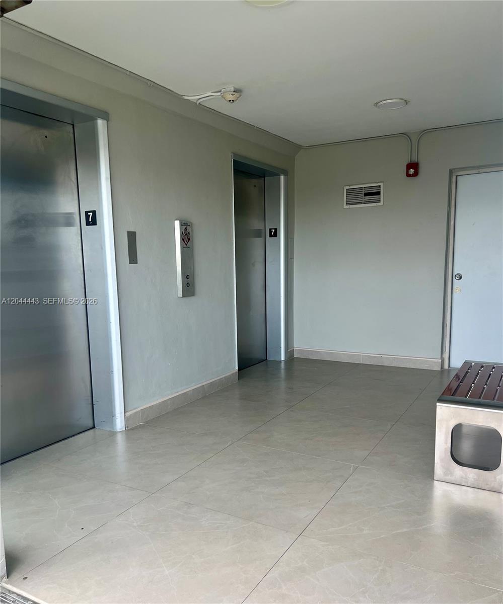 This elevator lobby features two metal elevator doors, light-colored tile flooring, and a white door — 1780 NE 191st St # 2, Miami FL 33179, MIAMI, FL