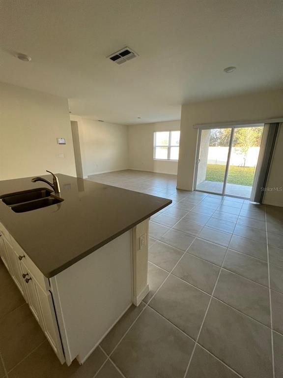 A kitchen island with a sink overlooks an open living area with tile flooring — 2710 TRINIDAD ROAD, HAINES CITY, FL