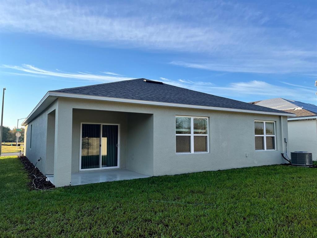 The rear exterior of a single-story house features a covered patio and two windows — 2710 TRINIDAD ROAD, HAINES CITY, FL