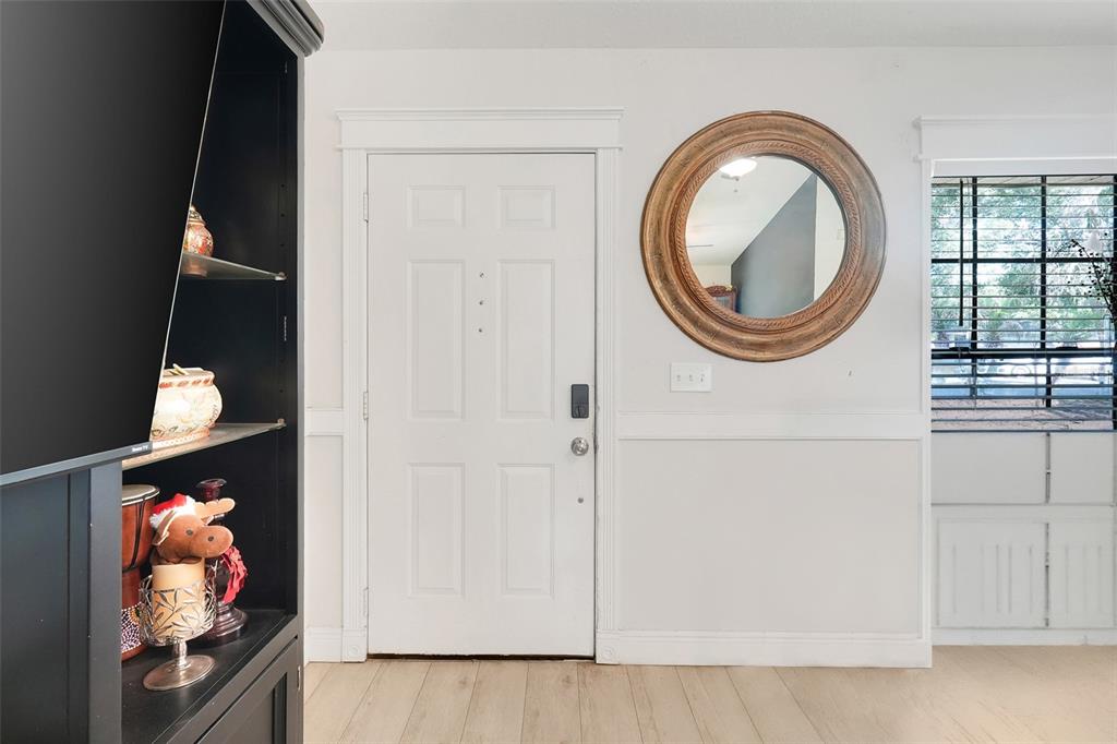 A white front door, a round wooden mirror, and a black shelving unit in a room — 207 HOWARD COURT, MASCOTTE, FL