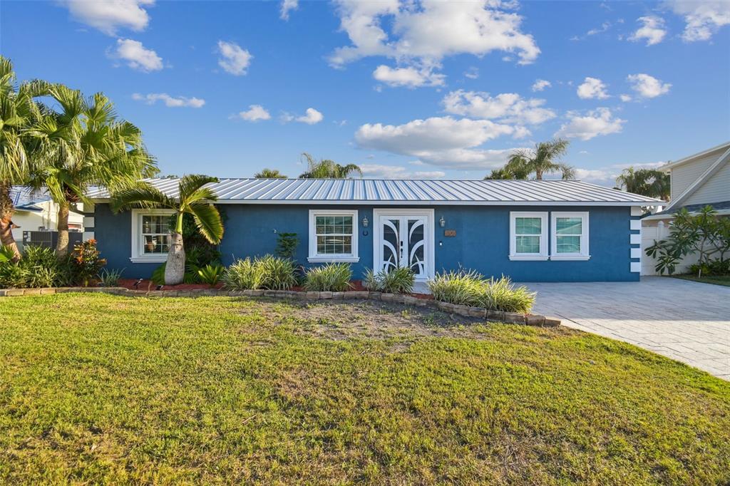 A blue single-story house with a white metal roof and a paved driveway — 8708 THORNWOOD LANE, TAMPA, FL