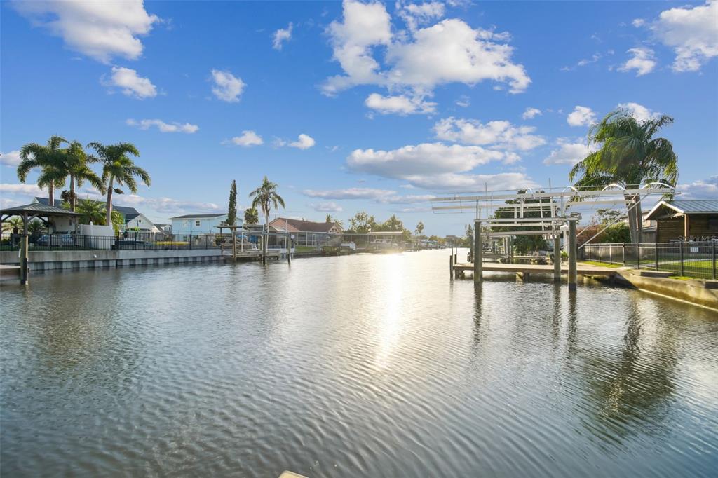 A canal view features boat docks, palm trees, and residential homes under a blue sky — 8708 THORNWOOD LANE, TAMPA, FL