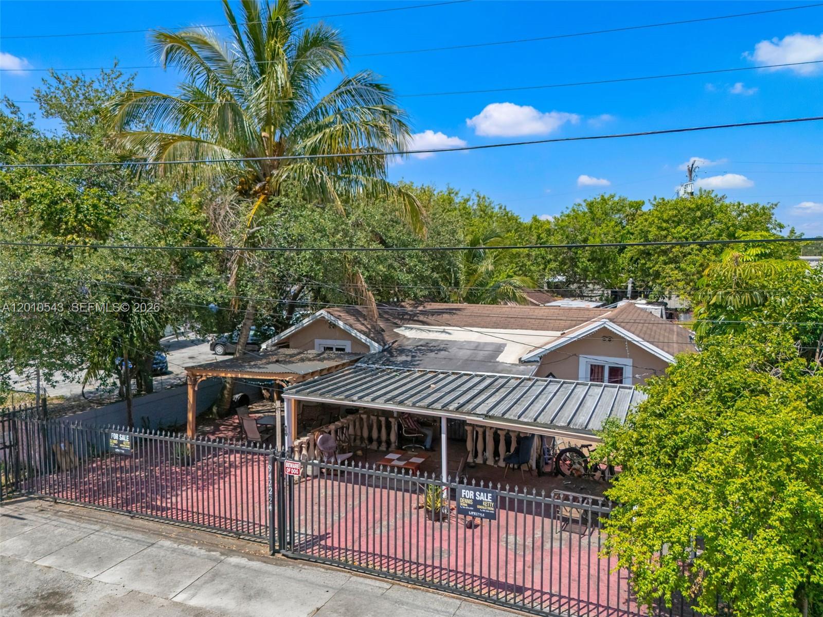 An exterior view of a single-story house with a metal-roofed carport and fenced yard — 9422 NW 26th Ave, Miami FL 33147, MIAMI, FL
