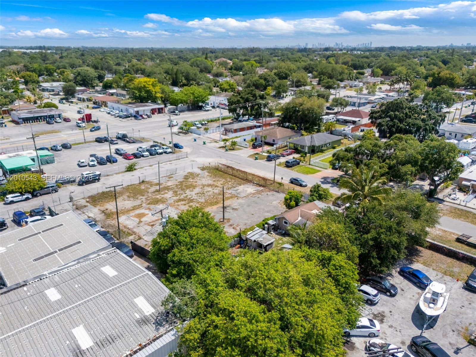 An aerial view shows a vacant lot surrounded by commercial buildings, houses, and parked vehicles — 9422 NW 26th Ave, Miami FL 33147, MIAMI, FL