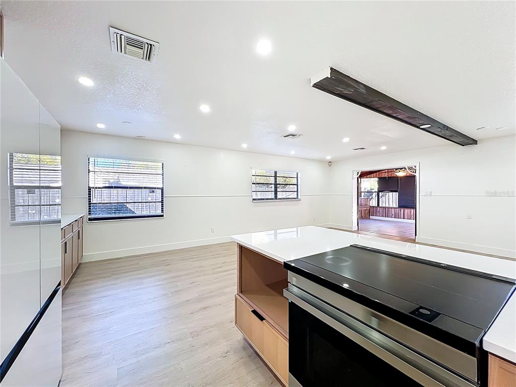 A kitchen features a large island with a cooktop, light wood cabinets, and white walls — 3463 ARNEL DRIVE, WINTER PARK, FL