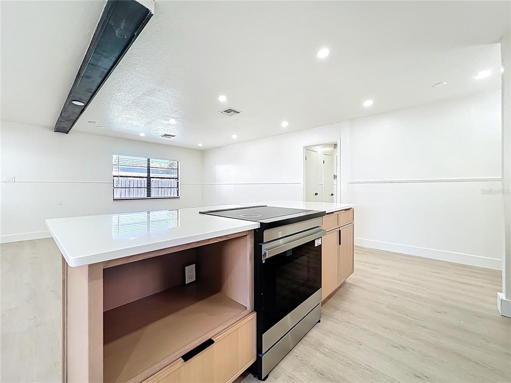 A kitchen island with a built-in range and light wood cabinetry sits in a room — 3463 ARNEL DRIVE, WINTER PARK, FL