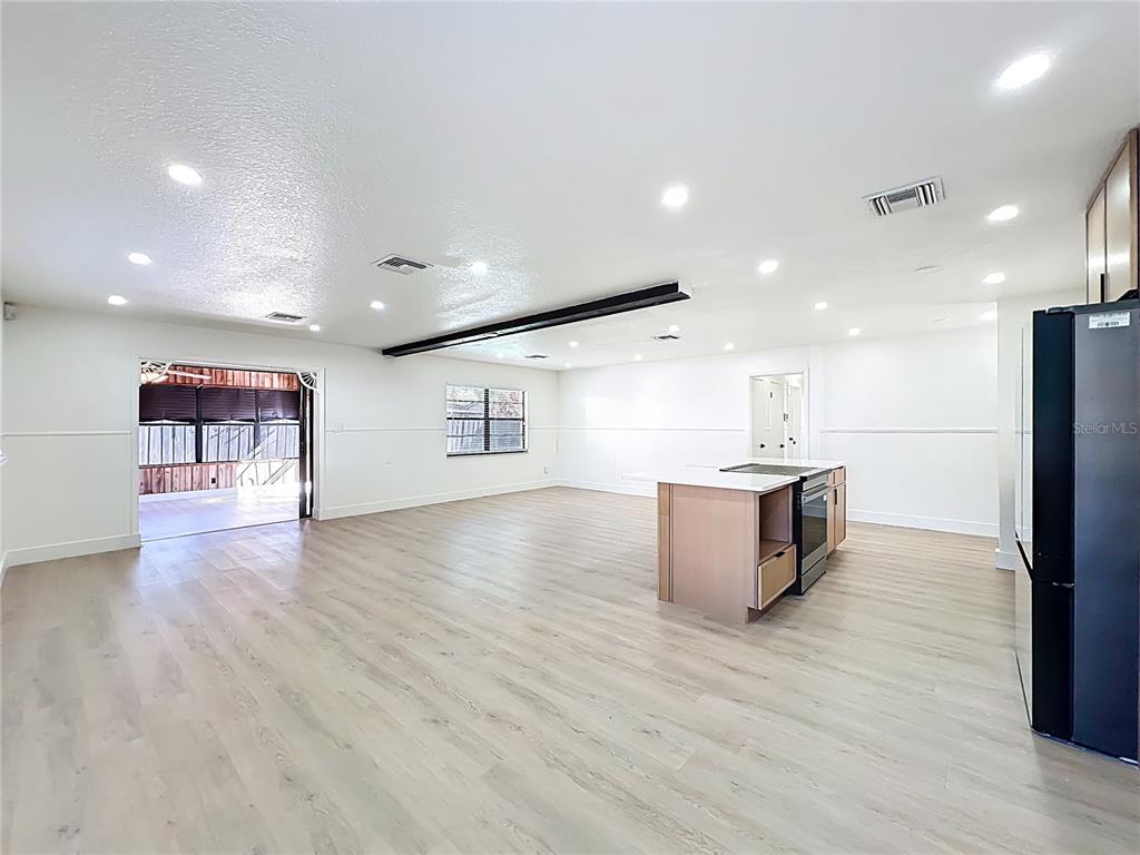 An open-concept kitchen and living area features light wood flooring and a central island — 3463 ARNEL DRIVE, WINTER PARK, FL