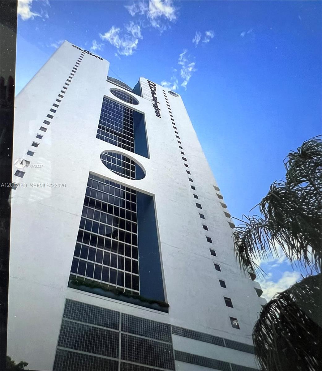 A low-angle view of a tall white residential building with rectangular windows and circular accents — 1717 N Bayshore Dr # A1448, Miami FL 33132, MIAMI, FL