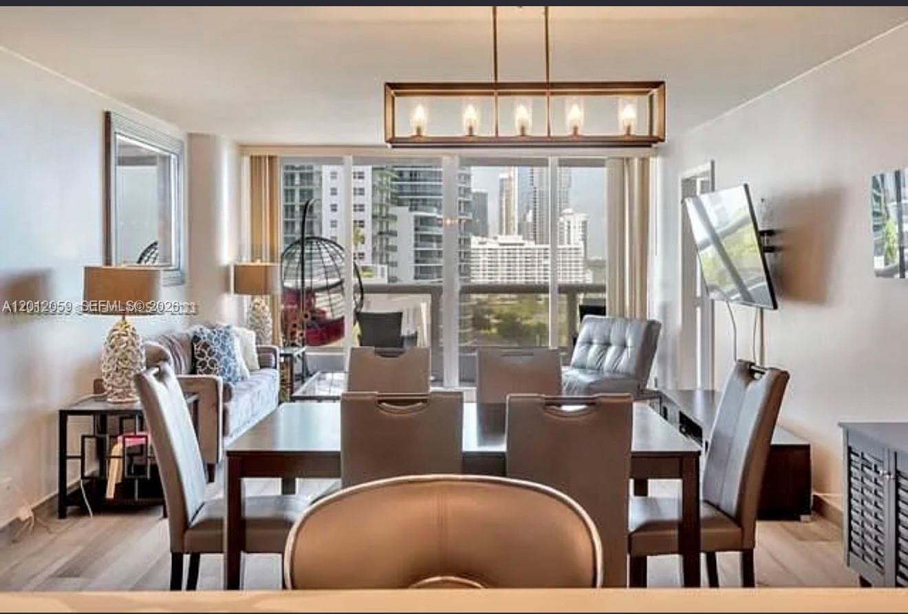 A dining area and living room with modern furniture, a large light fixture, and balcony views — 1717 N Bayshore Dr # A1448, Miami FL 33132, MIAMI, FL