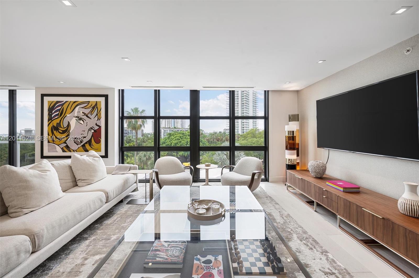 A modern living room features a glass coffee table, white sofa, and floor-to-ceiling windows — 9 Island Ave # 514, Miami Beach FL 33139, MIAMI BEACH, FL