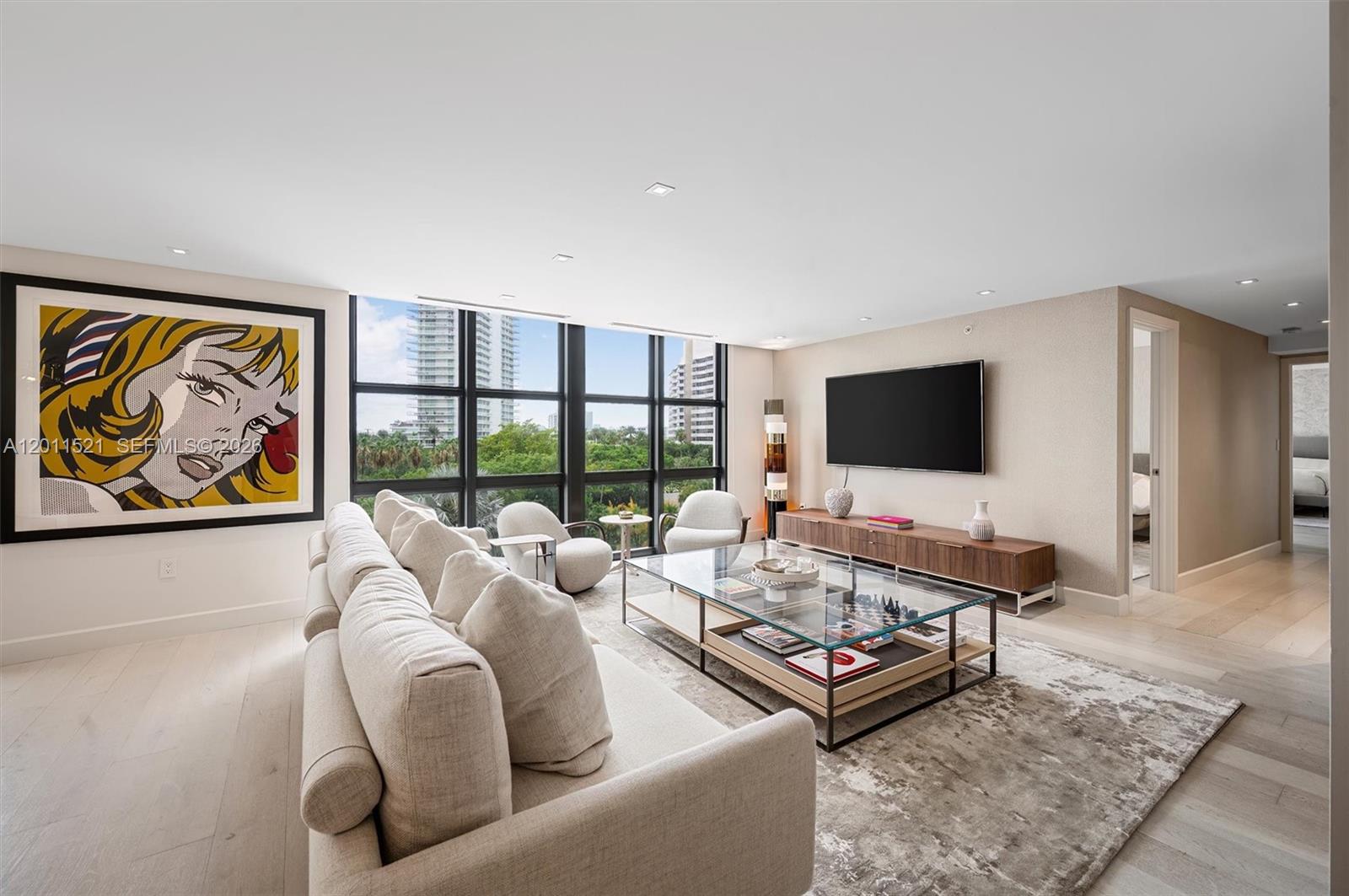A modern living room features a large sofa, glass coffee table, and pop art painting — 9 Island Ave # 514, Miami Beach FL 33139, MIAMI BEACH, FL
