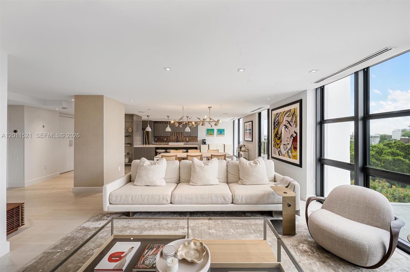 A modern living room features a beige sofa, a coffee table, and floor-to-ceiling windows — 9 Island Ave # 514, Miami Beach FL 33139, MIAMI BEACH, FL