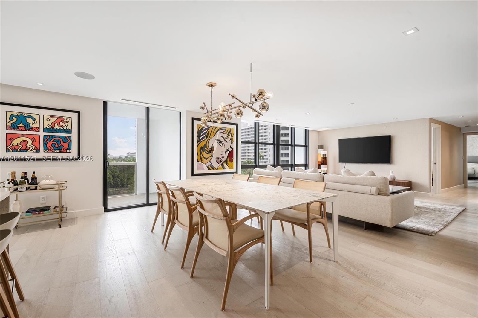 A dining area with a marble table and modern chandelier opens to a living room — 9 Island Ave # 514, Miami Beach FL 33139, MIAMI BEACH, FL