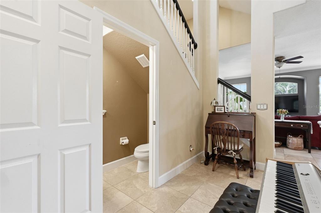 A view of a tiled entryway featuring a half bathroom, a wooden desk, and stairs — 2656 TANGLEWOOD TRAIL, PALM HARBOR, FL