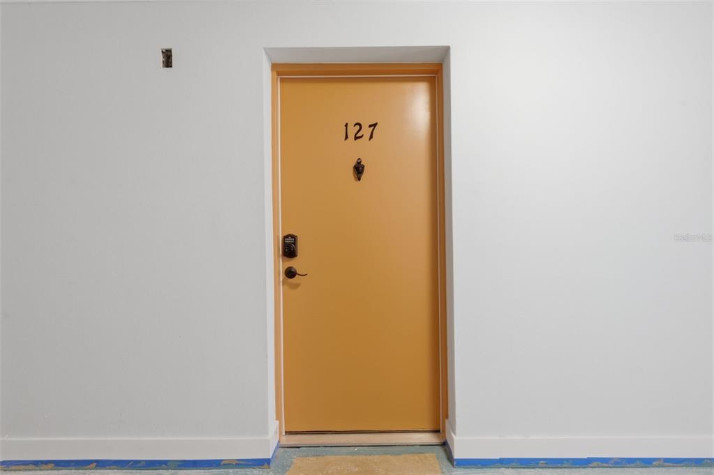 A yellow door labeled 127 is centered in a plain white wall — 8901 BLIND PASS ROAD UNIT 127, ST PETE BEACH, FL