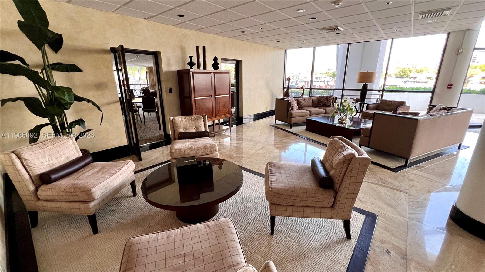 A spacious lobby features beige tile floors, multiple seating areas, and large floor-to-ceiling windows — 300 Three Islands Blvd # 520, Hallandale Beach FL 33009, HALLANDALE BEACH, FL
