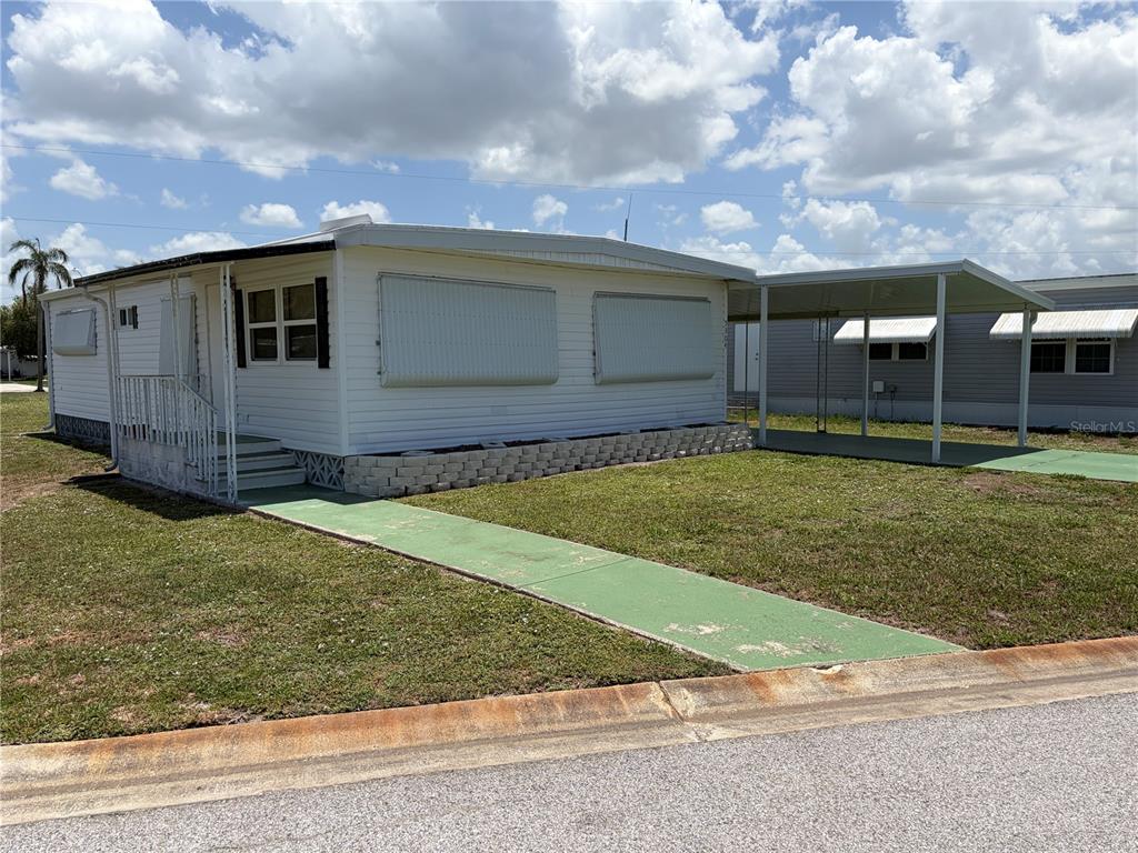 A white mobile home with a carport, green walkway, and stone landscaping border — 5304 CHERRY HILL AVENUE, SARASOTA, FL