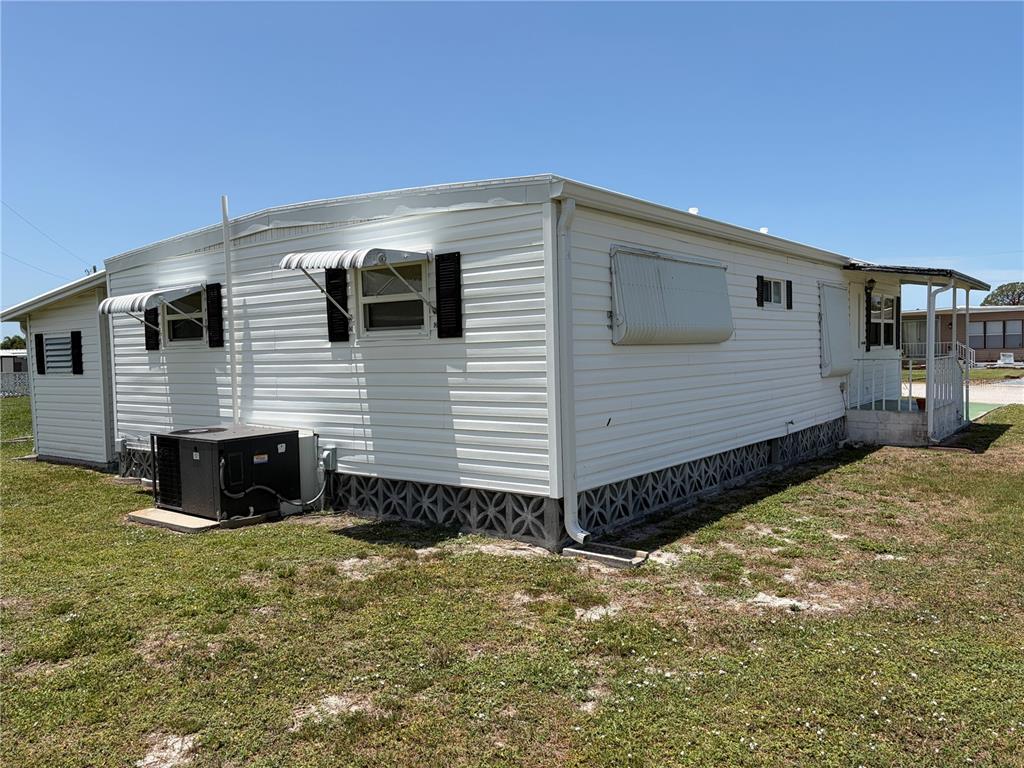 The exterior of a white mobile home features vinyl siding, metal awnings, and lattice skirting — 5304 CHERRY HILL AVENUE, SARASOTA, FL