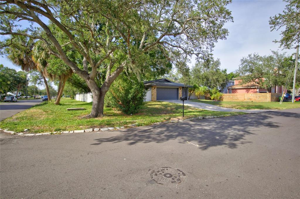 A single-story house with a gray garage sits on a corner lot with large trees — 7312 S FITZGERALD STREET, TAMPA, FL