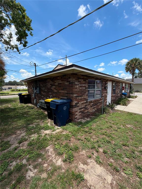Exterior view of a single-story brick apartment building with trash bins and utility meters — 223 ORANGE STREET UNIT 1-6, AUBURNDALE, FL