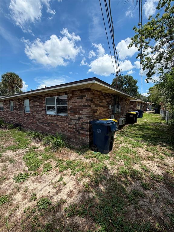 A brick exterior of a single-story building with trash bins along the side wall — 223 ORANGE STREET UNIT 1-6, AUBURNDALE, FL