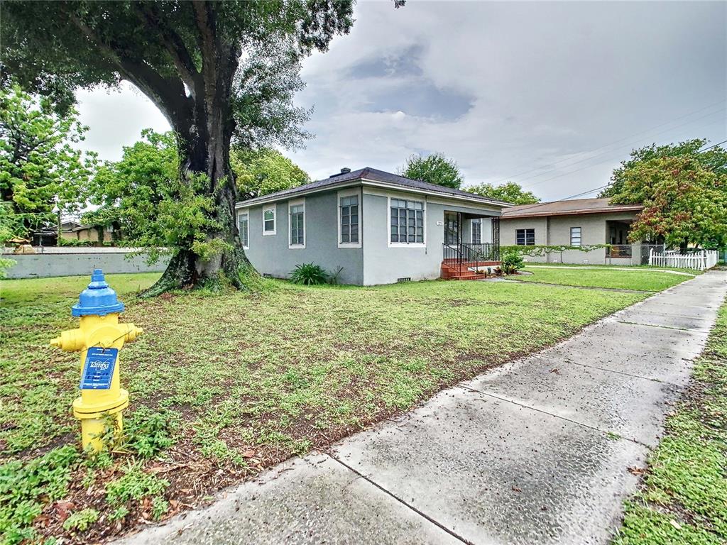 A yellow fire hydrant stands on a grassy lawn in front of a gray house — 2211 DURHAM STREET, TAMPA, FL