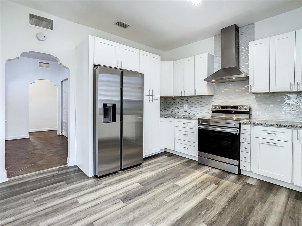 A modern kitchen features white cabinets, stainless steel appliances, and wood-look flooring — 2211 DURHAM STREET, TAMPA, FL