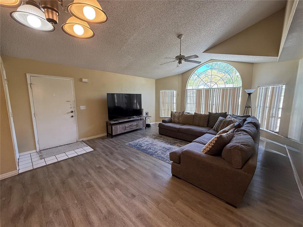A living room features wood-look flooring, a large sectional sofa, and an arched window — 2006 ROYAL BAY BOULEVARD UNIT 126, KISSIMMEE, FL