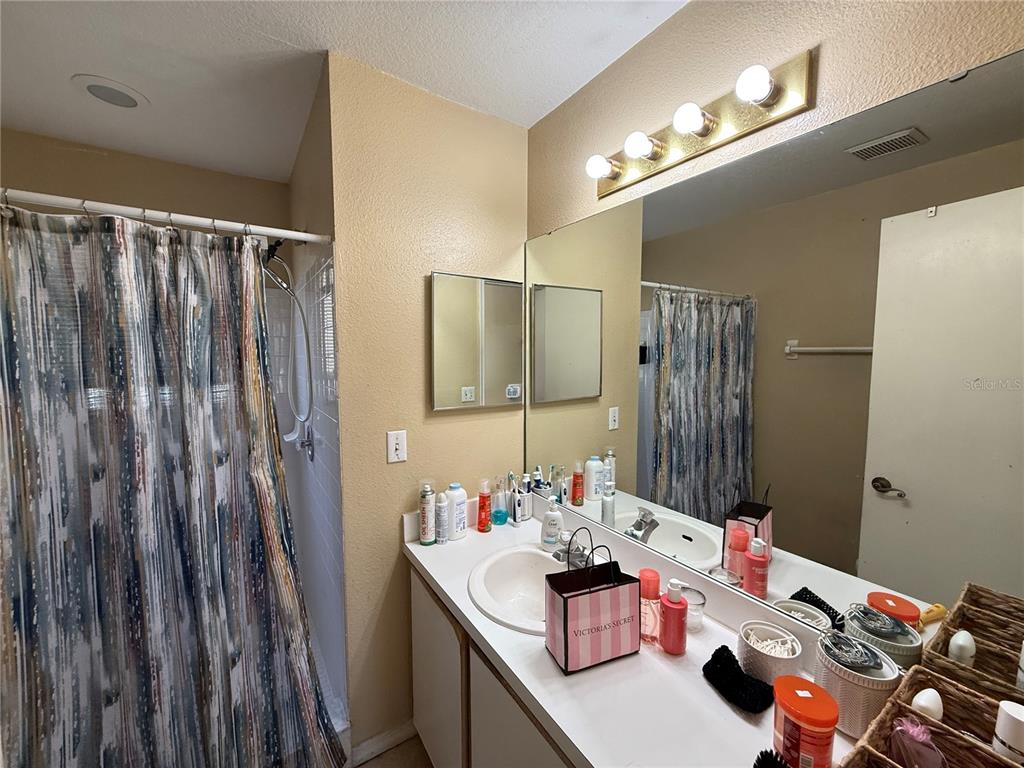 A bathroom features a vanity with a sink, a large mirror, and a shower curtain — 2006 ROYAL BAY BOULEVARD UNIT 126, KISSIMMEE, FL